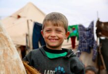 A young boy standing next to a wooden pole