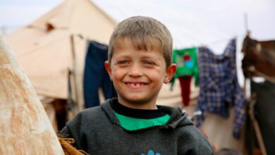 A young boy standing next to a wooden pole