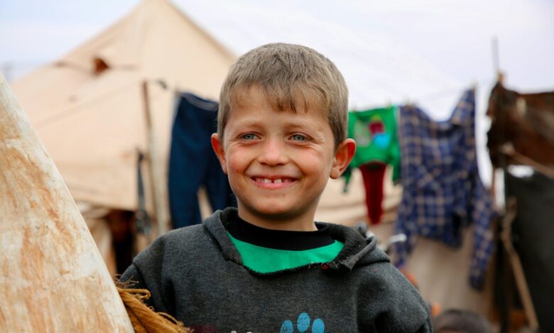 A young boy standing next to a wooden pole
